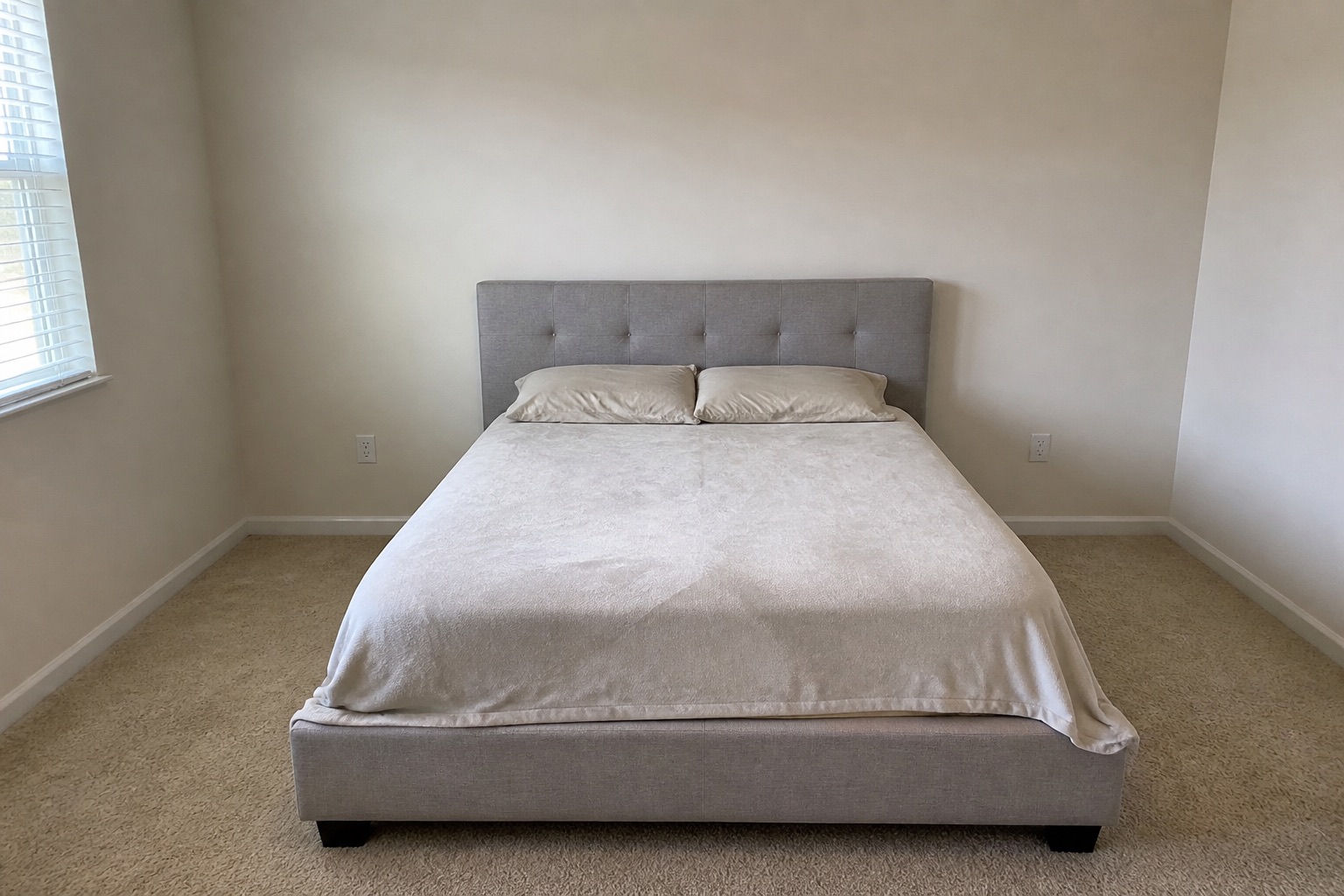 Room with grey upholstered bed, before